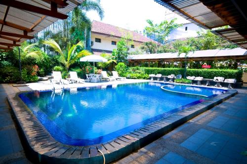 a swimming pool in a resort with tables and chairs at Mutiara Hotel and Convention in Bandung