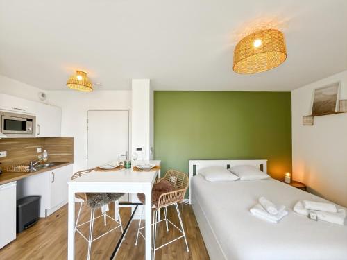 Cette chambre comprend un lit, une table et une cuisine. dans l'établissement Escale Dinardaise - Balcon & Garage Privé - Plage, à Dinard