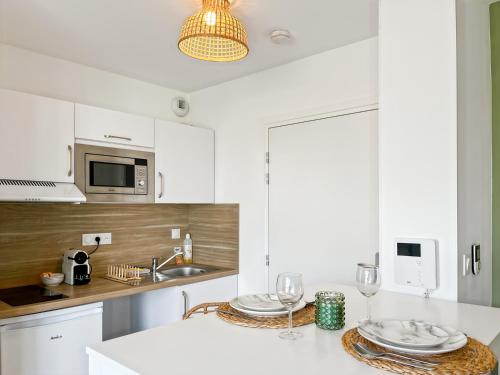 une cuisine avec des placards blancs et un comptoir blanc dans l'établissement Escale Dinardaise - Balcon & Garage Privé - Plage, à Dinard