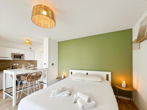 une chambre avec un lit blanc et un mur vert dans l'établissement Escale Dinardaise - Balcon & Garage Privé - Plage, à Dinard