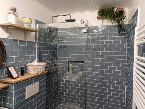 a blue tile bathroom with a glass shower at O'TY'ZOISEAUX - Plus proche de la nature - Meublé tourisme classé 4 étoiles in Scaër