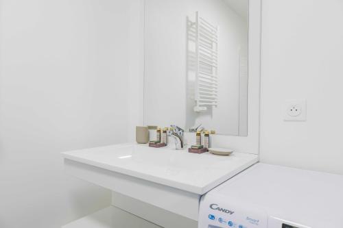 une salle de bain blanche avec un lavabo et un miroir dans l'établissement Classy apartment - Flea Market, à Saint-Ouen
