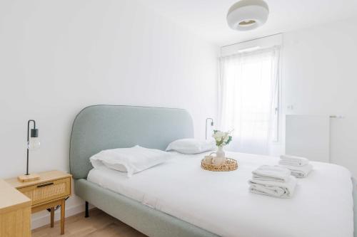 une chambre blanche avec un lit avec des serviettes dessus dans l'établissement Classy apartment - Flea Market, à Saint-Ouen