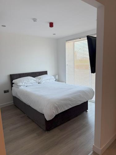 a bedroom with a large bed with white sheets and a window at Coastal Plaza in Blackpool