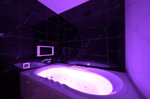 a purple bathroom with a tub with a tv on it at Hotel Victoria Court Aasahikawa-Adult Only in Asahikawa
