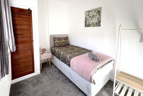 a small bedroom with a bed with a pink blanket at PLEASANT View Impressive Home In Stunning Rhondda Valley By Staystaycations in Pontypridd