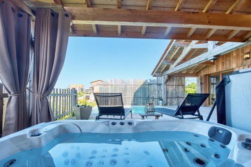 a jacuzzi tub on a patio with two chairs at Les cabanes de Monbazillac in Monbazillac