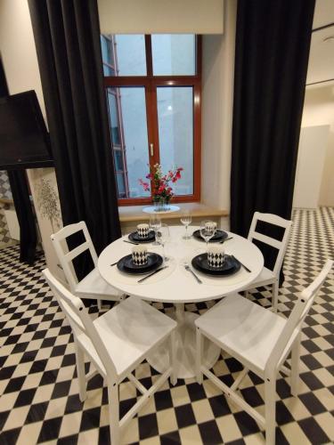 a white table and chairs in a room with a piano at Chessboard apartment in old town Riga, Coffee included in Rīga