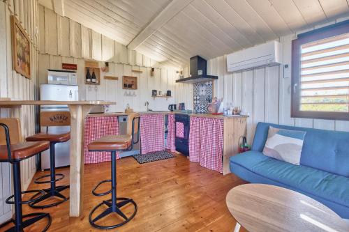 a living room with a blue couch and a kitchen at Les cabanes de Monbazillac in Monbazillac