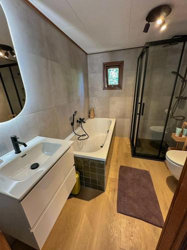 a bathroom with a tub and a sink and a shower at Boshuisjes Veluwe Lila met omheinde tuin in Putten