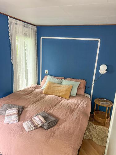a bedroom with a large bed with a blue wall at Boshuisjes Veluwe Lila met omheinde tuin in Putten