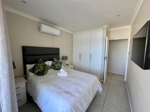 a bedroom with a white bed and a television at 71 Sea Lodge Beachfront Apartment in Durban