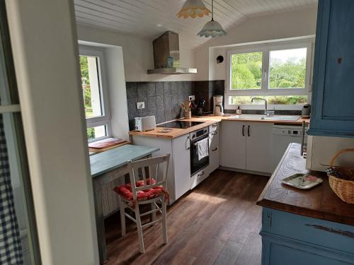 - une cuisine avec des appareils électroménagers blancs et 2 fenêtres dans l'établissement O'TY'ZOISEAUX - Plus proche de la nature - Meublé tourisme classé 4 étoiles, à Scaër
