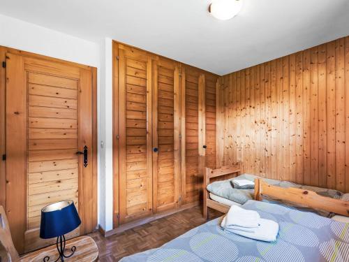 a bedroom with two beds and wooden walls at Chalet Moulinettes 8 by Interhome in Bluche