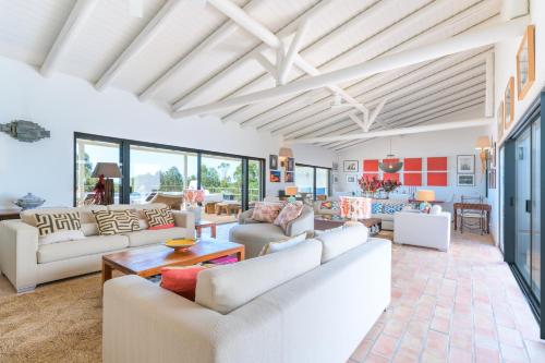 a living room with white furniture and windows at Monte da Torre in Melides