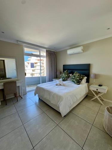 a bedroom with a bed and a desk and a window at 71 Sea Lodge Beachfront Apartment in Durban