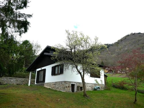 a white house with a black roof and a tree at Holiday Home Chalet Al Portic by Interhome in Scona