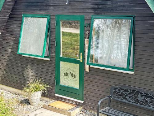 a house with a green door and two windows at Chalet Waldrauschen by Interhome in Bad Arolsen