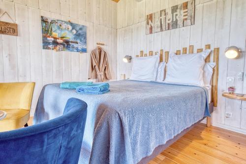 a bedroom with a bed with a blue blanket and a chair at Les cabanes de Monbazillac in Monbazillac