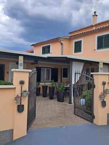 a house with a gate and potted plants at Apartments Anđela in Skradin