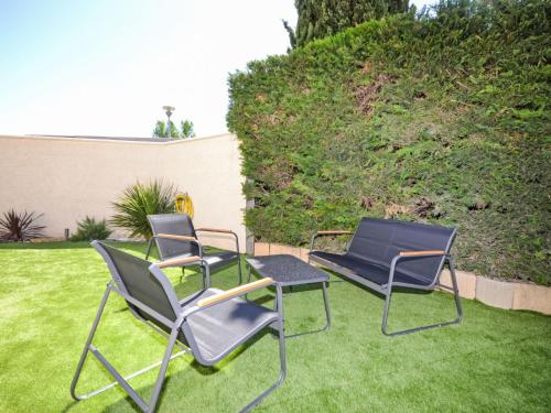 2 chaises et une table sur une pelouse dans l'établissement Holiday Home La Superbe by Interhome, à Piolenc