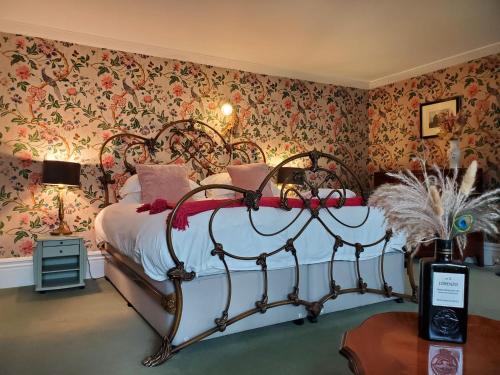 a bedroom with a bed with floral wallpaper at The Hall - Historic Grade I-listed Jacobean Mansion in Bradford on Avon