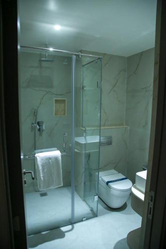 a bathroom with a glass shower with a toilet and a sink at Leaf Hotel in Tiruvannāmalai