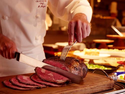 a chef cutting a piece of meat with a knife and fork at Nishitetsu Grand Hotel in Fukuoka