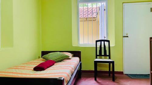 a bed in a green room with a window at The Old Manor - Weligama in Weligama