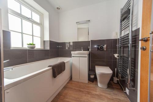 een badkamer met een bad, een toilet en een wastafel bij Central Warwick townhouse within easy reach of Stratford upon Avon and Cotswolds in Warwick