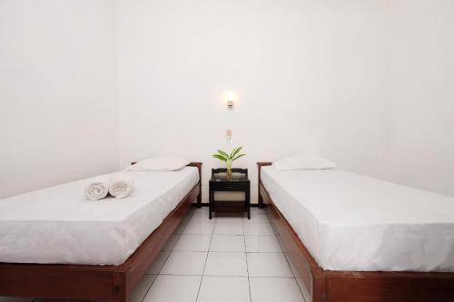 two beds in a room with a plant on a table at Berlian Abadi Hotel by Sinergi in Banyuwangi