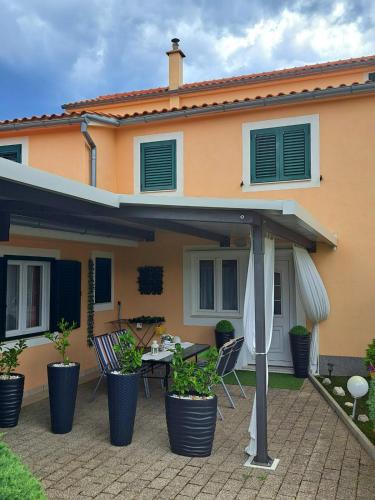 a house with a patio with chairs and an umbrella at Apartments Anđela in Skradin