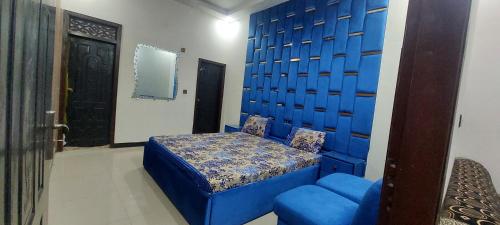 a bedroom with a blue bed and a blue chair at HostHub Guest House Gulshan iqbal in Karachi