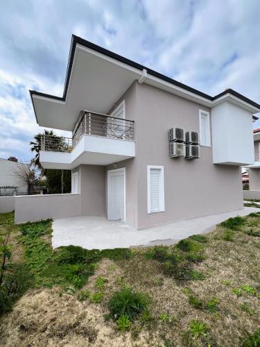 a white house with a balcony in a yard at Ble Studios in Nikiti