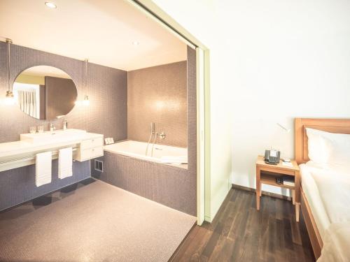a bathroom with two sinks and a tub and a bed at Resort Hof Weissbad in Weissbad