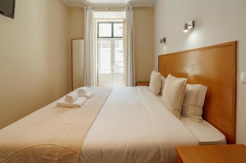 a bedroom with a large white bed with a window at Rossio Suites By Hosty in Lisbon