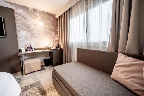 a bedroom with a bed and a desk and a window at Mercure Bordeaux Lac in Bordeaux