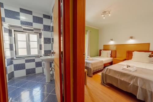 a room with two beds and a bathroom with a sink at Rossio Suites By Hosty in Lisbon
