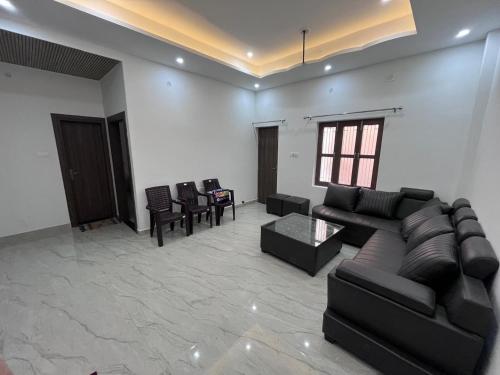 a living room with a black couch and chairs at Hridayam Kashi Homestay in Varanasi