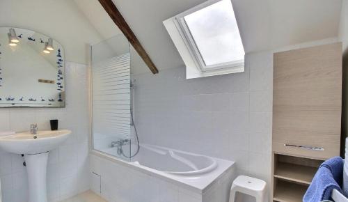 La salle de bains blanche est pourvue d'un lavabo et d'une baignoire. dans l'établissement Gite Abéria petite maison coquette, à Saint-Alban