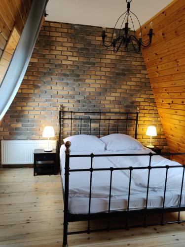 a bedroom with a metal bed in a brick wall at Szewilla in Szewnia