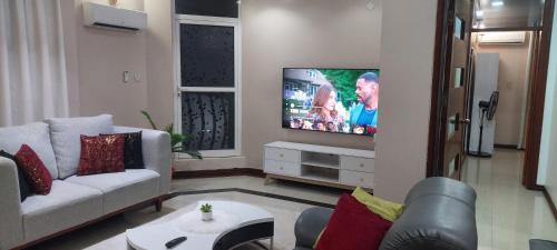 a living room with a couch and a flat screen tv at Sami BnB - Apt 02 Makongo after Mlimani City in Dar es Salaam