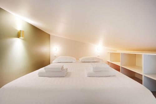 - un grand lit blanc avec des oreillers blancs dans l'établissement Chic and Cosy Apartment-Canal Saint Martin, à Paris