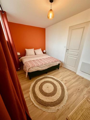 a bedroom with a bed with an orange wall at "Nuits du désert" - Appartement avec terrasse in Saint-Quentin