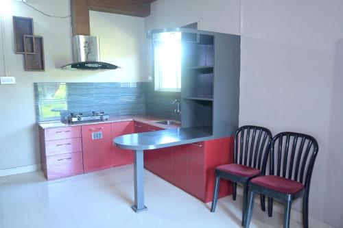 a kitchen with red cabinets and a table and two chairs at Rahaman Farm House in Lataguri