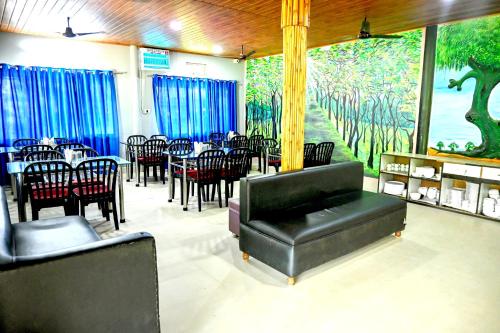 a restaurant with tables and chairs and a large mural at Rahaman Farm House in Lataguri
