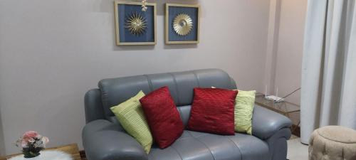 a leather couch with colorful pillows on it in a living room at Sami BnB - Apt 02 Makongo after Mlimani City in Dar es Salaam