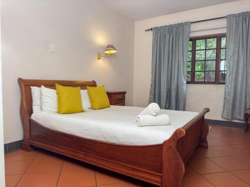 a bedroom with a bed with yellow pillows and a window at Park Gables Loftus Guest House in Pretoria