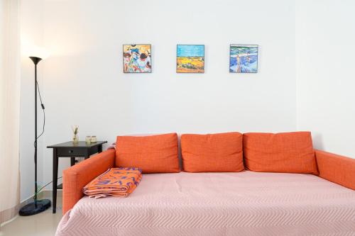 an orange couch with four pillows on it in a room at 1 Bed Apartment with pool La Red in El Campello