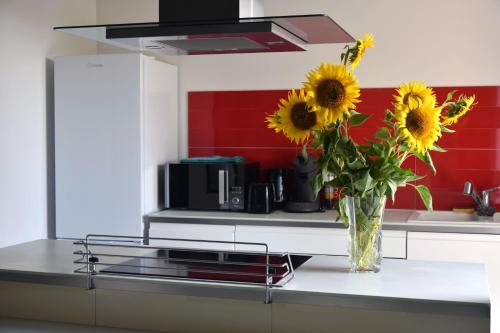 a vase of sunflowers sitting on a counter in a kitchen at Villa Spacieuse au Calme Absolu avec Grande Piscine Jacuzzi Chauffé - Grand Jardin Sans Vis a vis- Salle de Jeux avec Fresque du Nougat - Ideal Familles et Groupes Drome Provencale in Montélimar